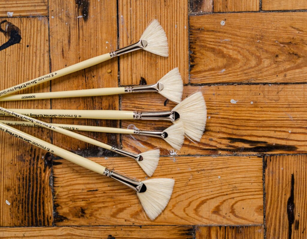 Two different types of paintbrushes on a wooden surface.