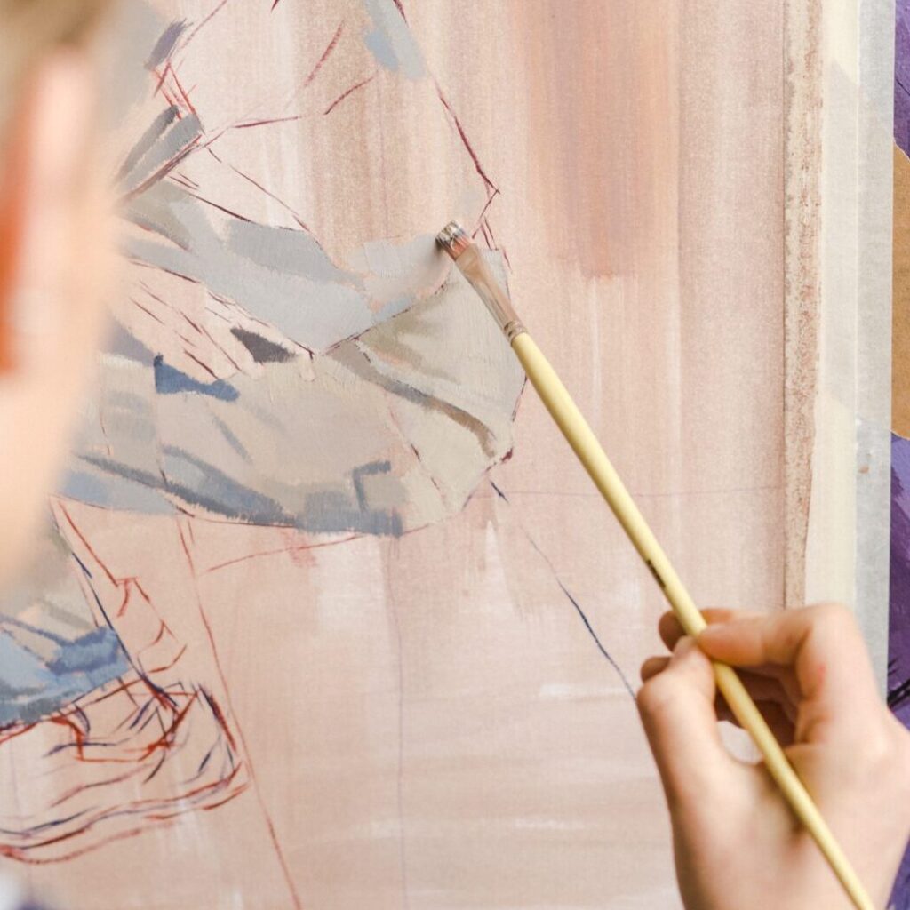 Images shows a close up of an artists working with a paintbrush to create abstract patterns