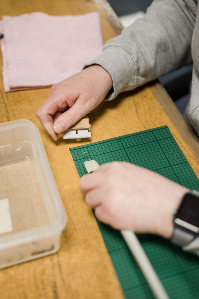 Image of someone lining up a paintbrush on a cutting board ready for cutting and finishing