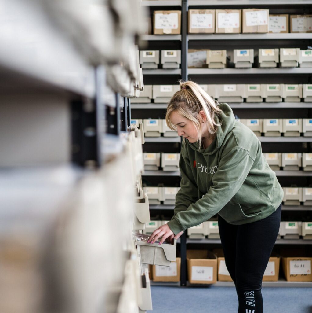 Image of a worker in a store room pulling a box off the shelf