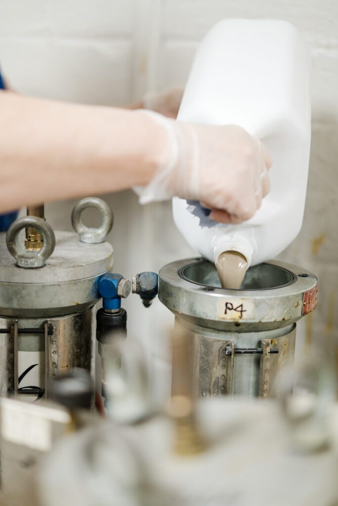 Image of glue being poured into a large silver machine