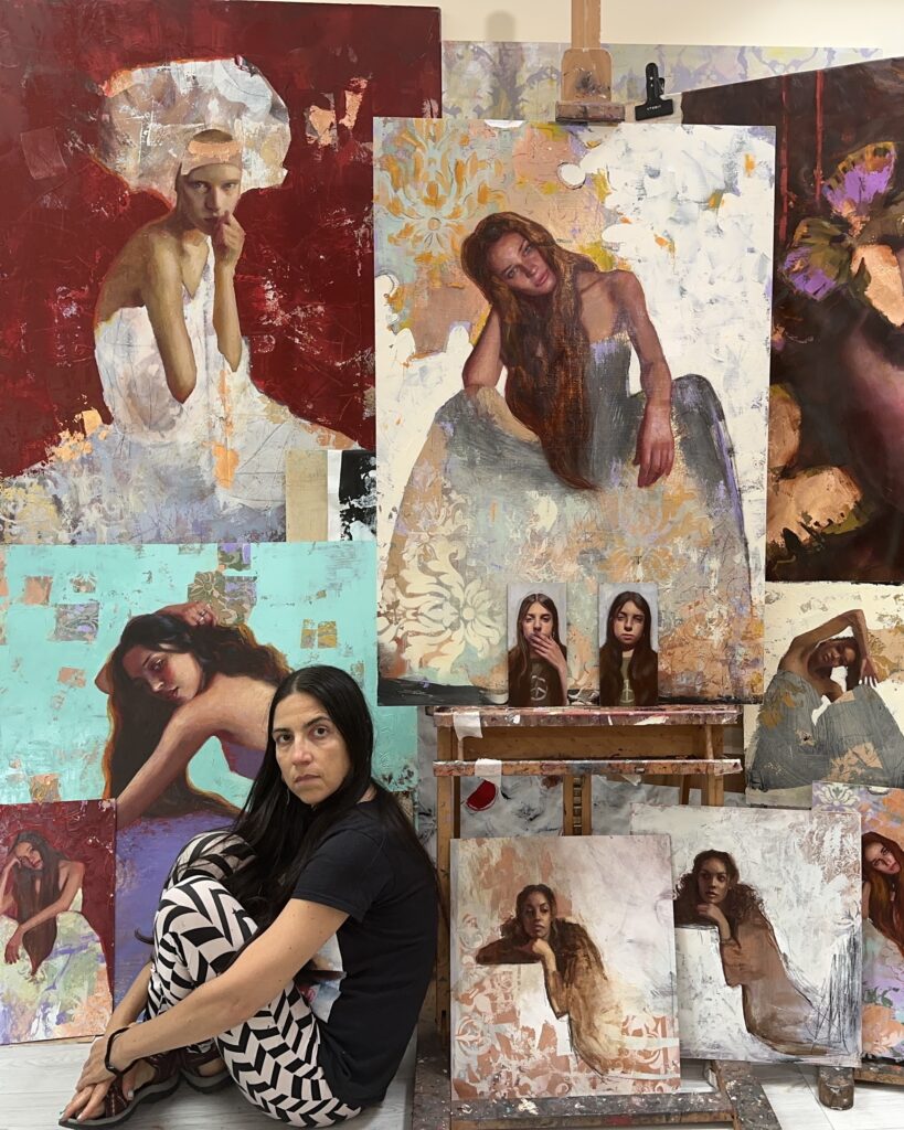 Rosso sitting down next to an array of oil paintings in her studio.